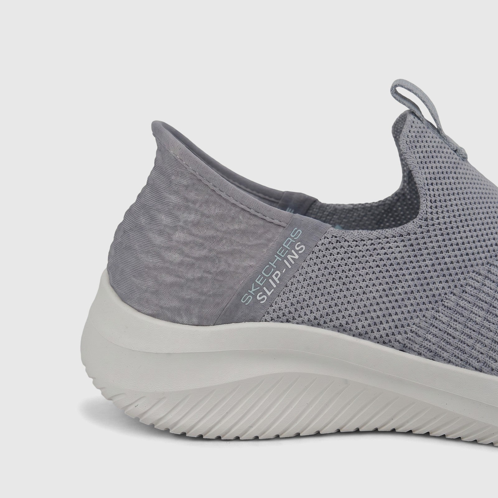 Close-up of a light grey Skechers Ladies Comfort Slip-Ins sneaker with a knit upper and white sole, shown at an angle.