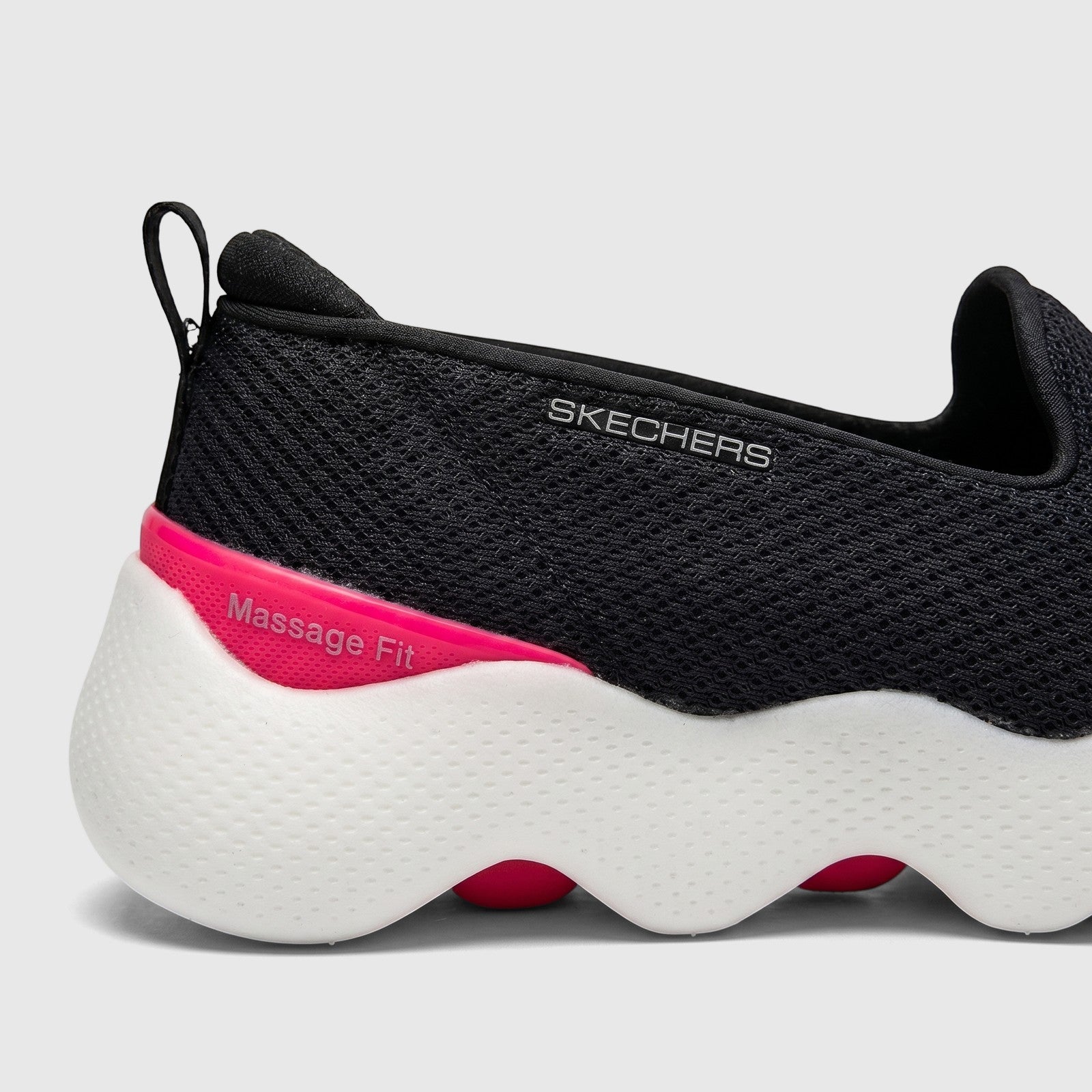Close-up side view of Skechers Ladies Go Walk Massage Fit slip-on sneakers in black and hot pink with a wavy white sole.