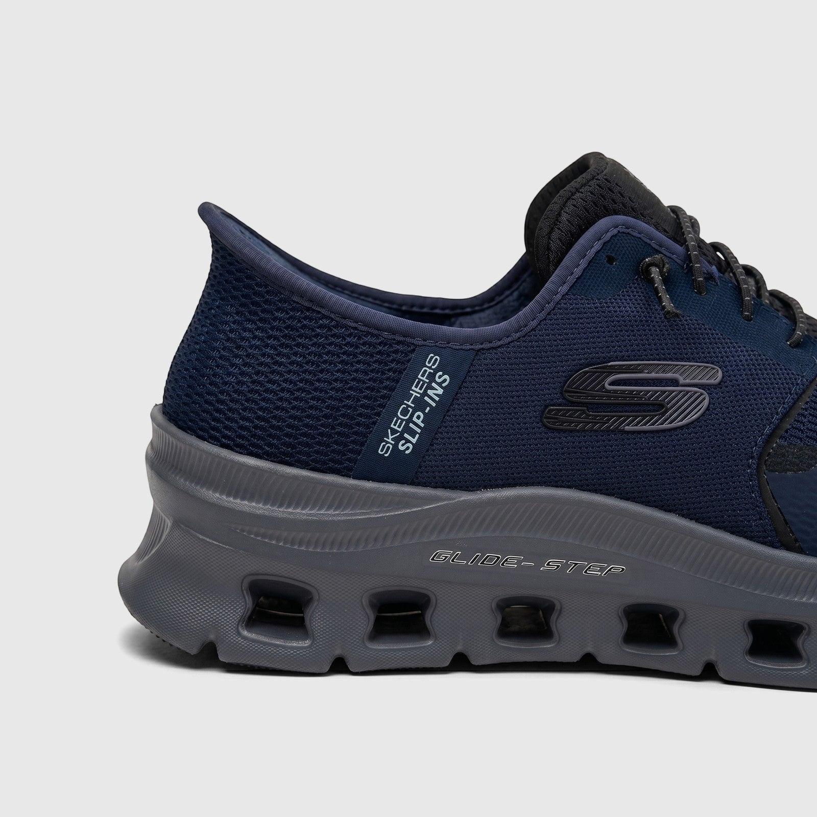 Side view of a Skechers Men's Glide-Step Pro comfort sneaker in navy blue and charcoal gray, showing mesh upper and unique