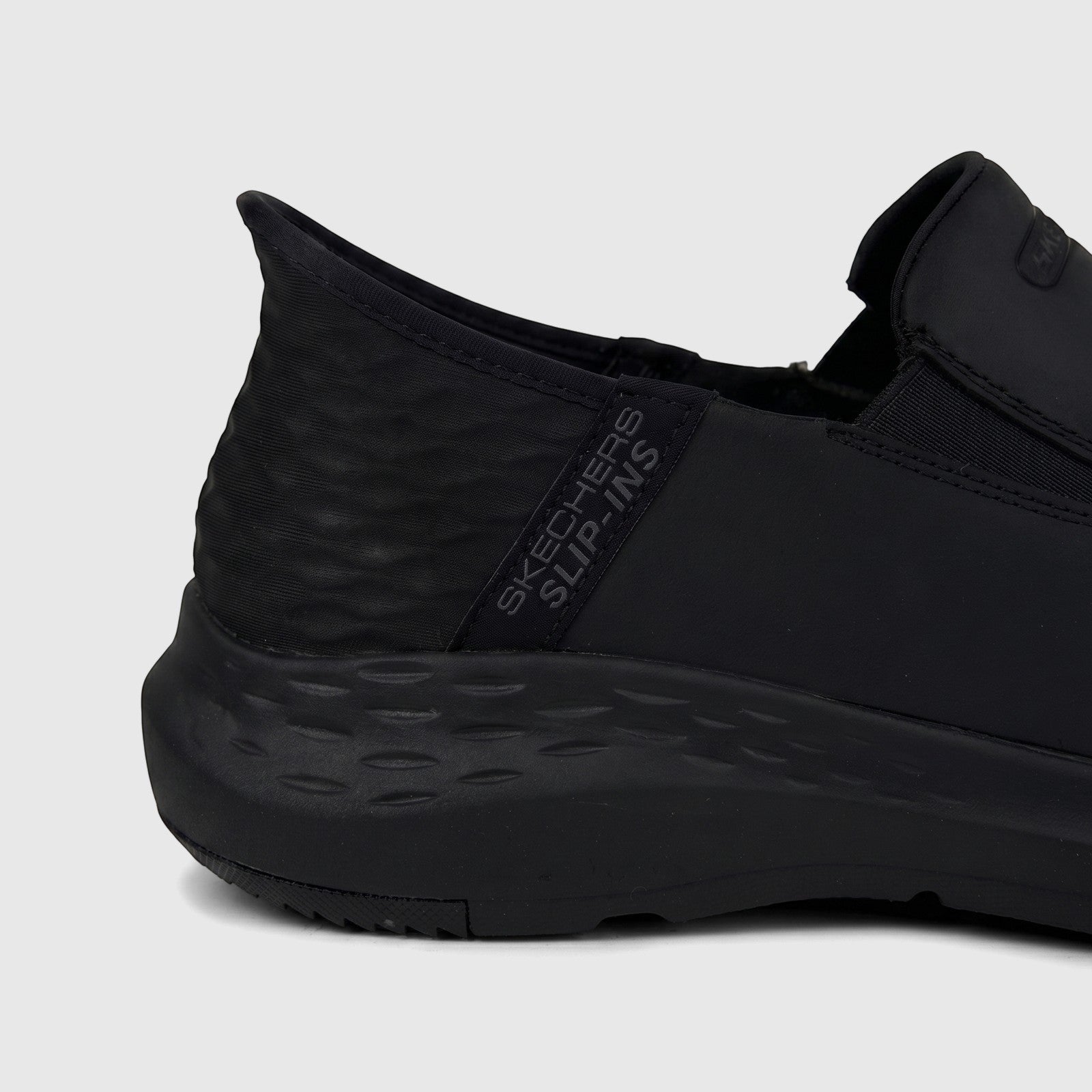 Skechers Men's Parson 204866 black slip-on comfort shoe. Side view, showing 'Skechers Slip-ins' branding, textured heel, and