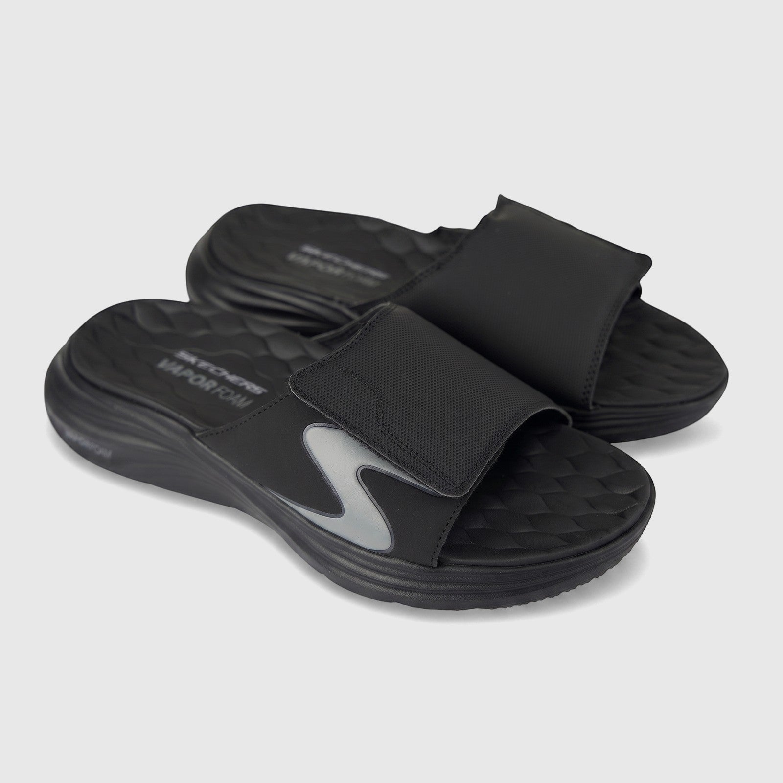 Pair of black Skechers Vapor Foam slide sandals with a gray S-logo and textured footbed on a clean background.