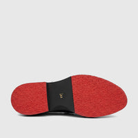 Unisex leather loafer with a chunky red and black sole, featuring a textured tread, viewed from the bottom.