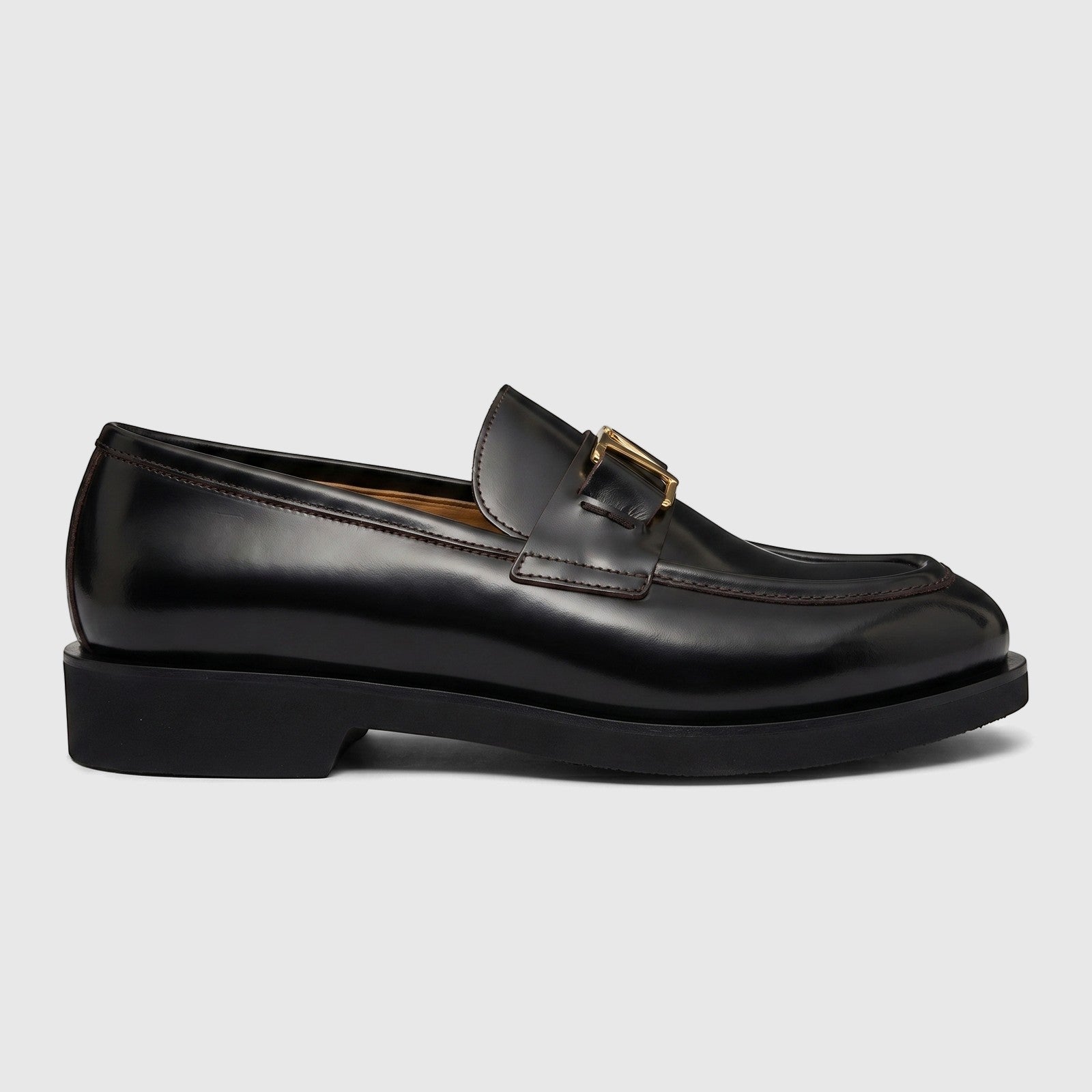 Black leather Valentino men's slip-on loafer with a chunky sole and gold-tone V-logo from a side view.