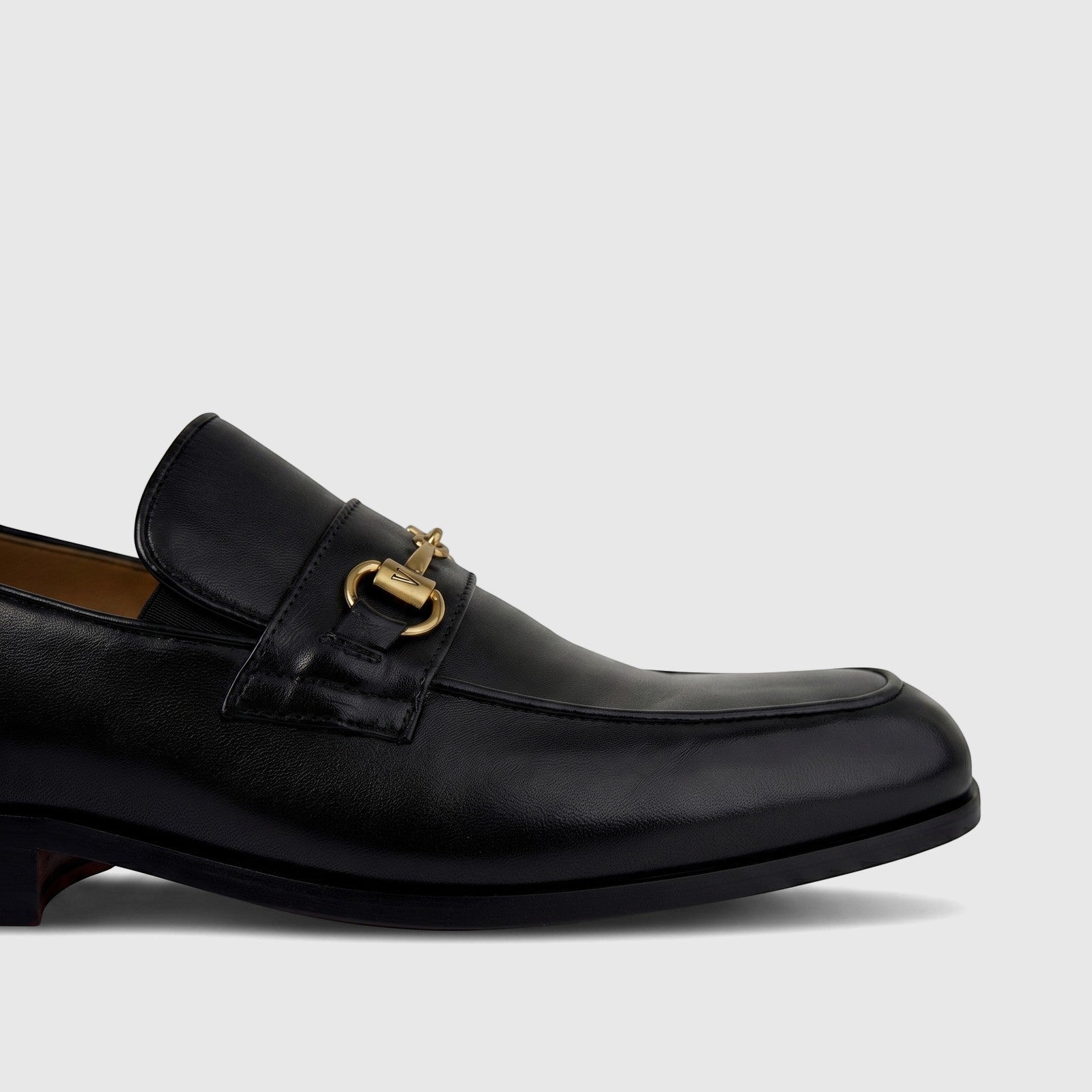 Black Valentino men's leather dress slip-on loafer with gold-tone horsebit hardware, shown in a close-up side view.