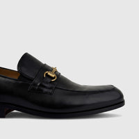 Black Valentino men's leather dress slip-on loafer with gold-tone horsebit hardware, shown in a close-up side view.