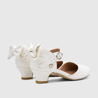 Pair of white girls' dress heels with decorative bows on the back and an ankle strap with a silver buckle. Side view.